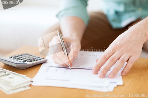 Image of close up of man counting money and making notes