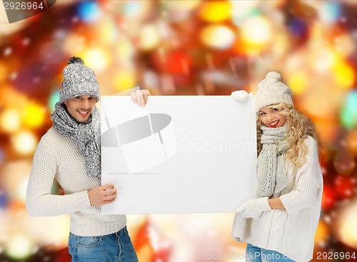 Image of smiling couple in winter clothes with blank board