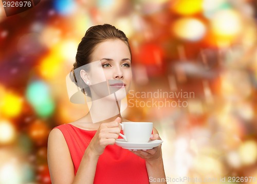 Image of smiling woman in red dress with cup of coffee