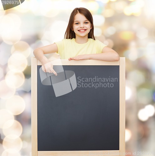 Image of happy little girl pointing finger to blackboard