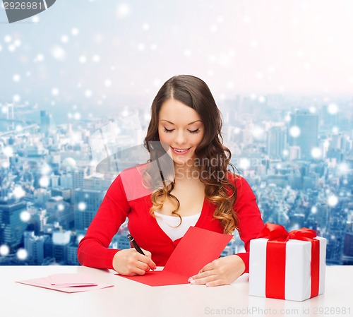 Image of smiling woman with gift box writing letter