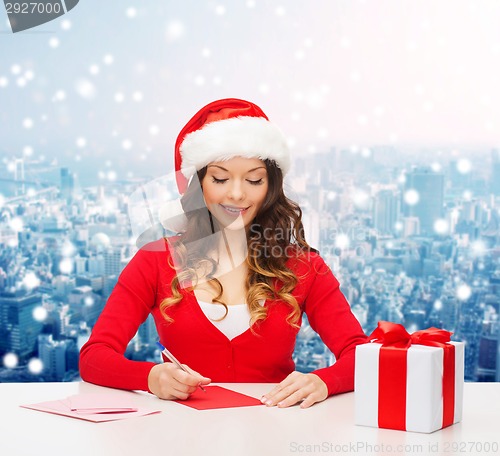 Image of smiling woman with gift box writing letter