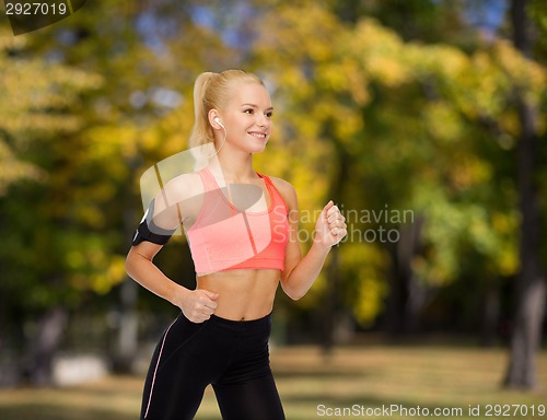 Image of sporty woman running with smartphone and earphones