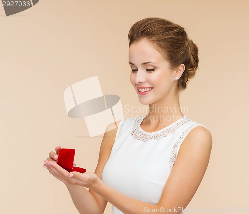 Image of smiling woman holding red gift box with ring