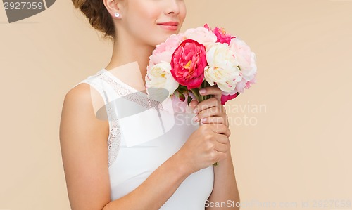 Image of smiling woman in white dress with bouquet of roses