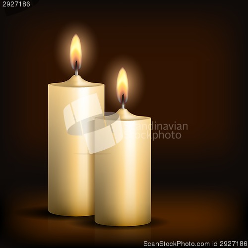Image of Two burning candles on black background.