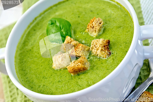 Image of Soup puree with spinach leaves and croutons on napkin