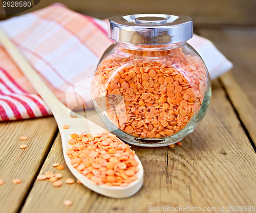 Image of Lentils red in jar and spoon with napkin on board