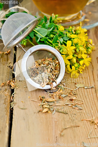 Image of Herbal tea from tutsan in strainer with cup on board