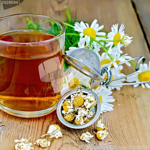 Image of Herbal chamomile tea in mug with strainer on board