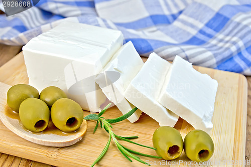 Image of Feta with olives and rosemary on board with blue cloth