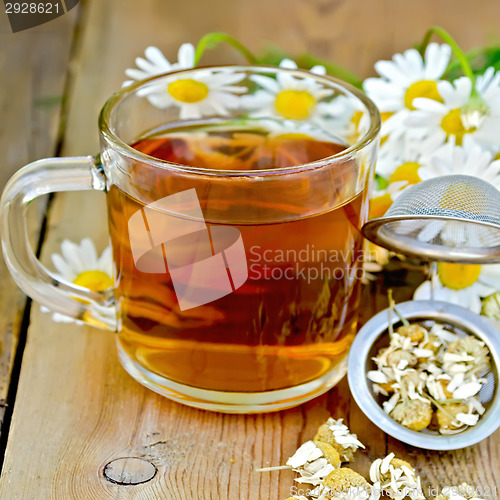 Image of Herbal chamomile tea in a mug with strainer on the board