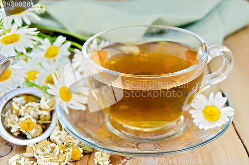 Image of Herbal chamomile tea in cup with strainer on board