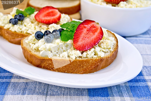 Image of Bread with curd and berries on blue checkered cloth