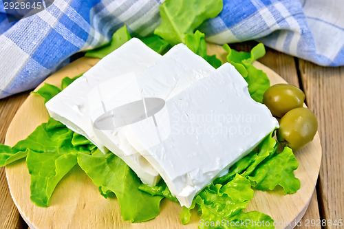 Image of Feta with olives and lettuce on board with blue cloth