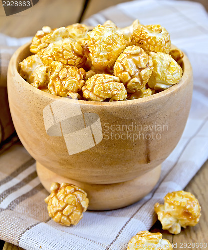 Image of Popcorn caramel in wooden bowl on board with napkin