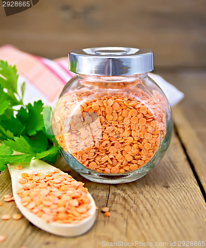 Image of Lentils red in jar and spoon on board with parsley