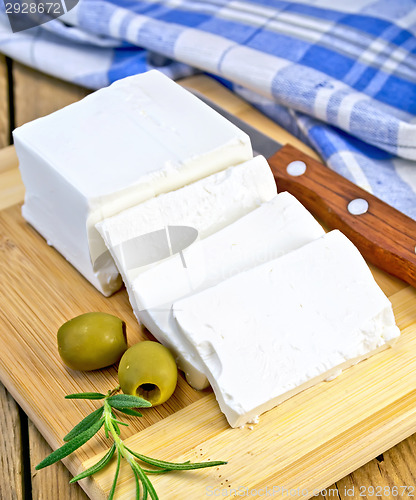 Image of Feta with olives and rosemary on board with knife