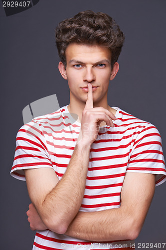 Image of Hush. Young serious sullen man with finger on lips