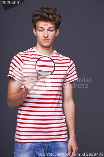 Image of Astonished man looking through a magnifying glass