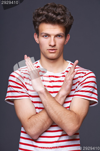 Image of Young serious man doing stop symbol