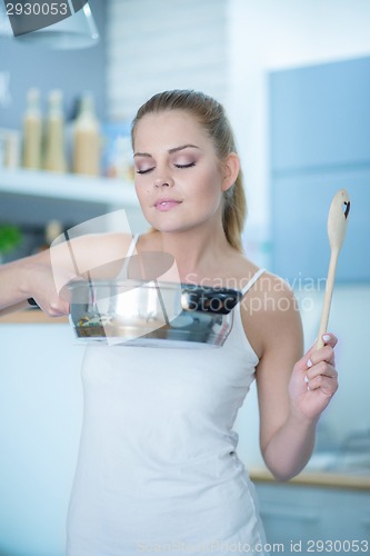 Image of Young woman savoring the smell of her cooking