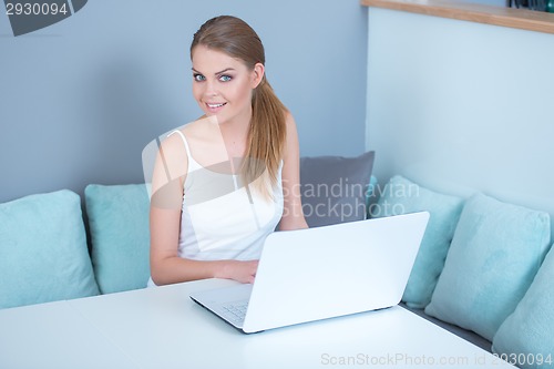 Image of Attractive woman sitting using a laptop at home
