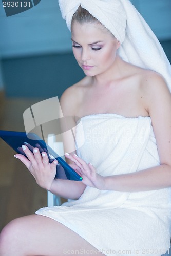Image of Woman in Bath Towel Looking at Tablet Computer