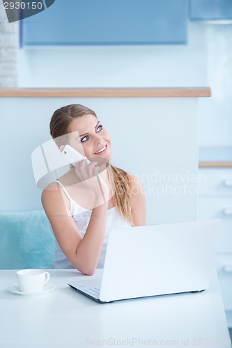 Image of Smiling woman sitting at a desk taking call