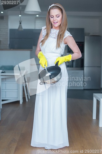 Image of Woman Wearing Wedding Gown Washing Pan in Kitchen