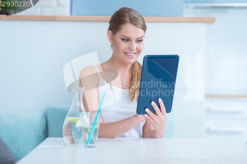 Image of Smiling pretty woman reading her tablet screen