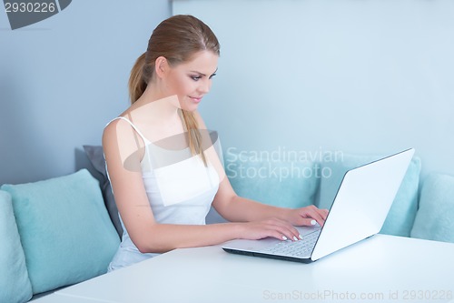 Image of Attractive young woman using a laptop at home