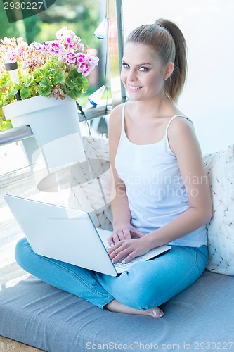 Image of Smiling young woman working outdoors on a porch