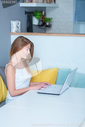 Image of Attractive young woman using a laptop at home