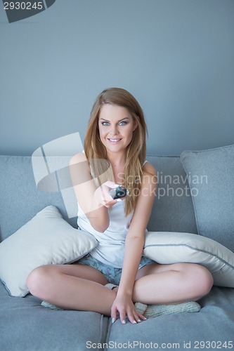 Image of Smiling gorgeous young woman watching TV