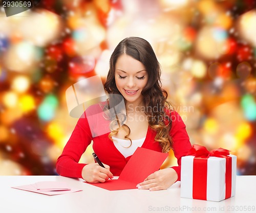 Image of smiling woman with gift box writing letter