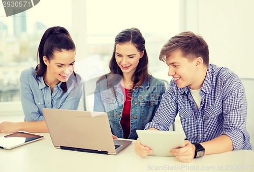 Image of three smiling students with laptop and tablet pc