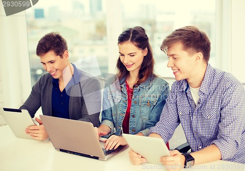 Image of three smiling students with laptop and tablet pc