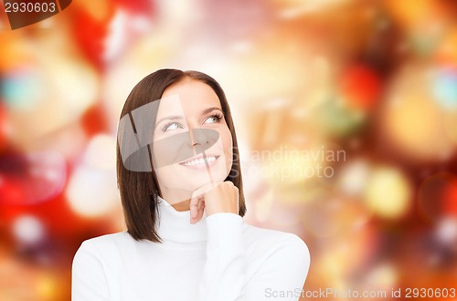 Image of thinking and smiling woman in white sweater