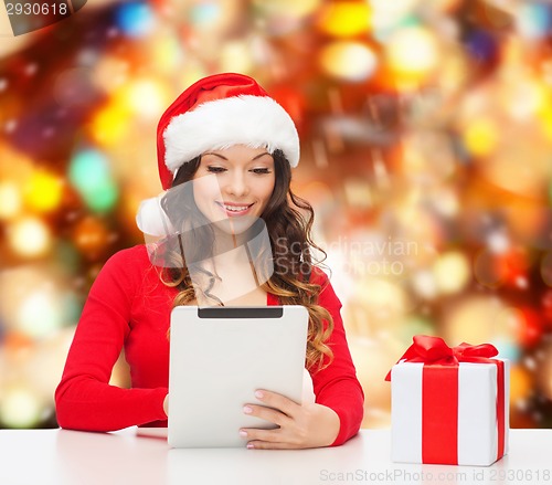 Image of smiling woman in santa hat with gift and tablet pc