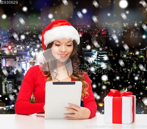 Image of smiling woman in santa hat with gift and tablet pc