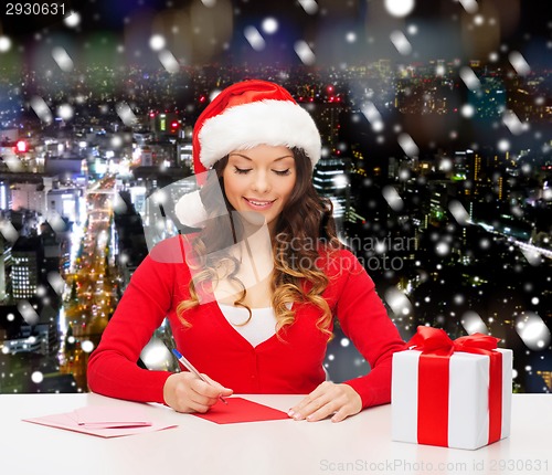 Image of smiling woman with gift box writing letter