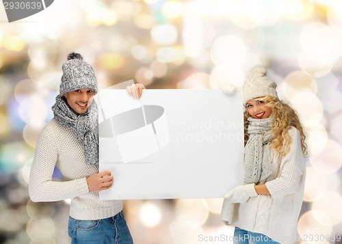 Image of smiling couple in winter clothes with blank board