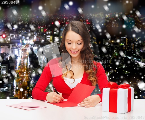 Image of smiling woman with gift box writing letter