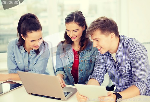 Image of three smiling students with laptop and tablet pc