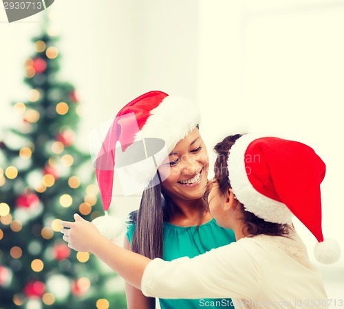 Image of hugging mother and daughter in santa helper hats