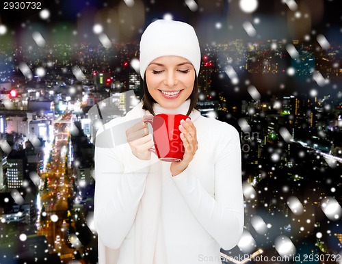 Image of smiling young woman in winter clothes with cup