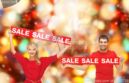 Image of smiling man and woman with red sale signs