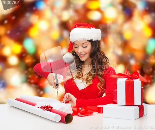 Image of smiling woman in santa helper hat packing gift box