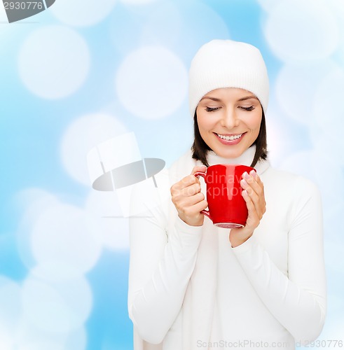 Image of smiling young woman in winter clothes with cup